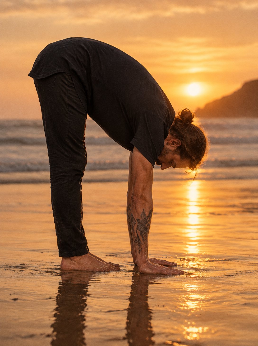 Deep forward fold on wet sand at sunset, the Flow Tee staying in place over his back